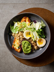 Plate with breakfast salads: avocado toast, egg, greens, fried cheese, quinoa