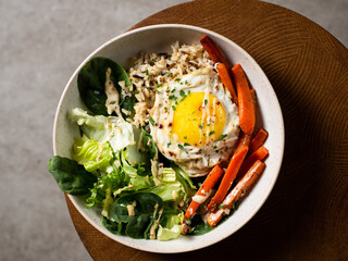 Plate with breakfast salads: brown rice, carrots, egg