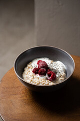 Healthy breakfast oatmeal porridge with yogurt and frozen raspberries in bowl. Warm porridge oats, vegan vegetarian weight loss dieting breakfast food