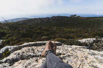 Vista en primera persona de paisaje de montaña con una mano sujetando una brújula y los pies de...