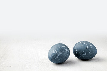 Two painted blue chicken eggs on a white background