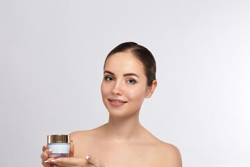 Beautiful young woman with clean fresh skin. Girl holding cream in her hand .Spa and face care
