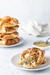 A serving of a baked pretzel served with mustard dip and a stack in behind.