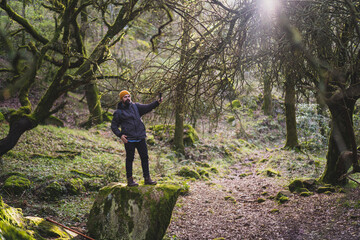 Obraz premium Chico con barba haciendo senderismo y haciéndose fotos sobre una roca