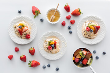 Top down view of homemade meringues topped with fresh fruit and honey.