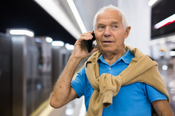 Old man with smartphone in subway station