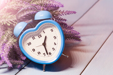 Blue heart-shaped alarm clock and lavender