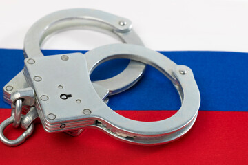 Obraz premium Handcuffs on the background of the Russian flag close-up.