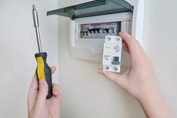 A woman changes an automatic fuse in a home electrical panel. Self repair and replacement of electricity equipment in the apartment, diy