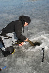 An ice angler releasing a pike 