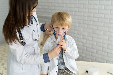 .Medical doctor applying medicine inhalation treatment on a little boy with asthma inhalation...