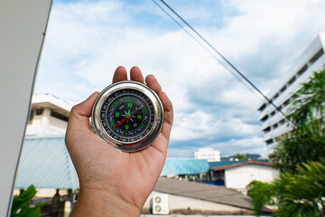 Hand holding a compass ready for a holiday adventure trip, it tells the direction north, south,...