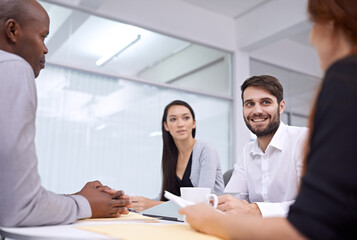 All smiles in the morning meeting. A group of coworkers sitting in an office and having a meeting.
