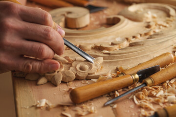 Wood carving. Carpenter's hands use chiesel. Senior wood carving professional during work. Man...