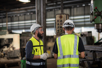 A new worker, latin mix race man worker have unkempt beard in safety uniform is being training on the job or coaching from a supervisor to control the heavy machine in industrial manufacturer factory.