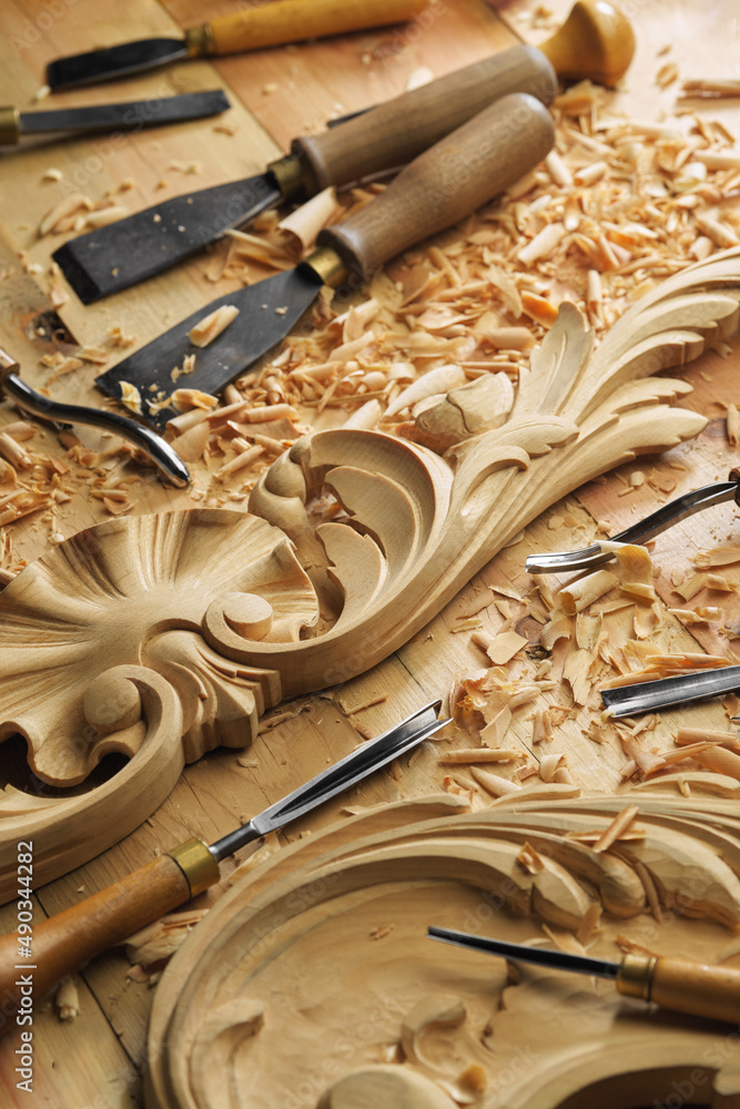 Wall mural Craftsman carving with a gouge. Woodwork. Workbench with equipment. Wood carving tools. Chisels for carving