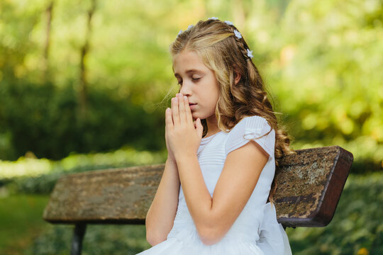Young woman praying on bench in park