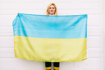 Ukrainian mature woman with blond hair serious gesture with blue and yellow Ukrainian flag on white...