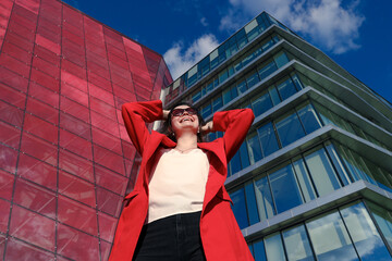 Portrait of a young woman in a red jacket on the background of glass buildings