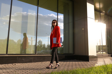 Fototapeta premium A young woman with a laptop walks in the background of the office