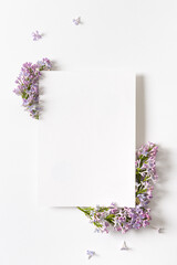 Invitation or greeting card with lilac flowers frame on white background. Spring floral mockup with copy space. Creative flat lay. Copy space for text. Springtime poster. Vertical