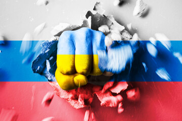 A fist punches through a concrete wall with the colors of the Ukrainian and russian flags. The...