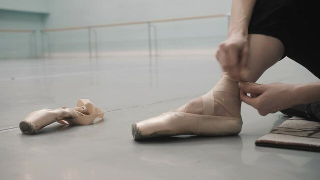 ballerina in the rehearsal room tying ballet flats. Preparing for rehearsal. close-up