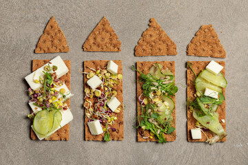 Healthy snack, snack. Finn crisps with pesto sauce, cucumber, tofu and micro greenery. Close-up on...