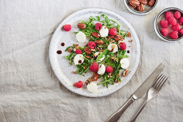 Summer salad with arugula, raspberries, mozzarella cheese and pecan nuts. Morning, breakfast, healthy food. Selective focus