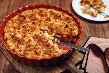 Mac and cheese. American Cheese pasta casserole with cheese sauce and crispy breadcrumbs in ceramic baking dish on wooden background. Selective focus - 490350268