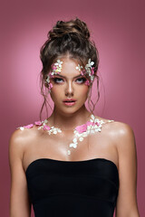 Beautiful caucasian woman with flowers on pink background.