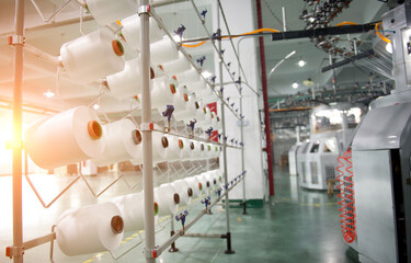 Textile industry - yarn spools on spinning machine in a textile factory - Powered by Adobe