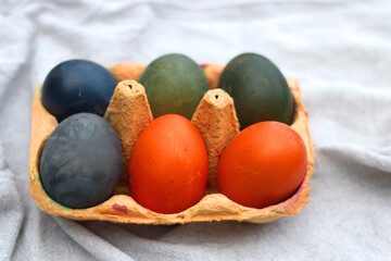 Ceramic bowl filled with painted Easter egss in jewel tones. Selective focus.