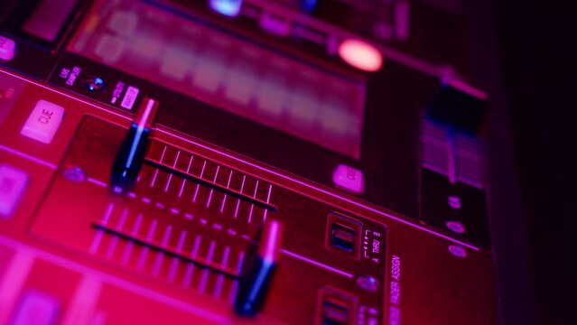 DJ hand presses button and moves fader on mixer console in disco club, closeup. Dj mixer controller desk in night club