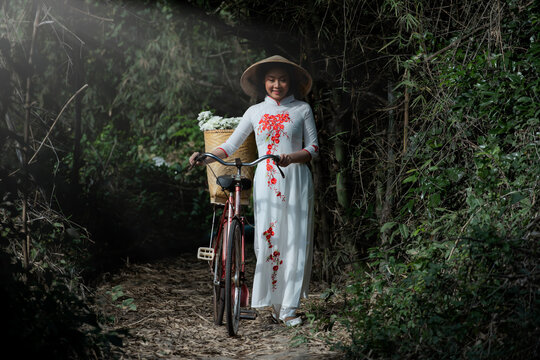 Thai girl dress fine art portrait of Thai woman wearing Vietnam dress with bicycle in wild.