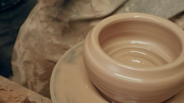 Apprentice learning clay pottery on ancient kick operated revolving wheel