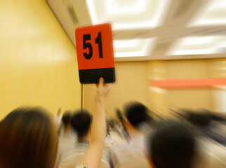 People holding auction paddle to buy from auction.