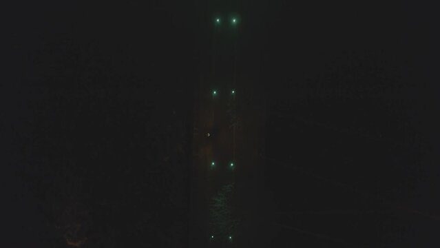 Bird's eye view of a pier beside River Corrib in Galway City with green lights aligned on the side in this night time shot. At the end is a rectangle gradient green light structure.