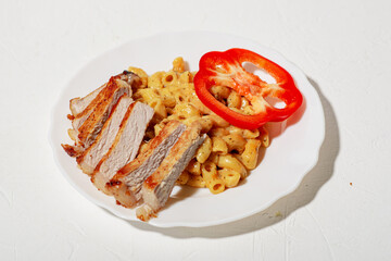 Figured Italian pasta in sauce. Pieces of chopped fried meat and sweet red pepper. Minimalistic food design. White background.