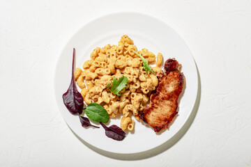 Pasta in cheese sauce with chopped meat and lettuce. Minimalistic food design. White background.