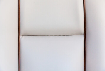 Texture of a white leather chair upholstery with brown accents close-up. White leather background.