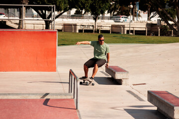 Fototapeta premium Man riding skateboard in urban street skatepark. Casual guy wearing shorts and T-shirt.