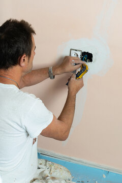 Electrician kneeling on the floor installing a plug socket