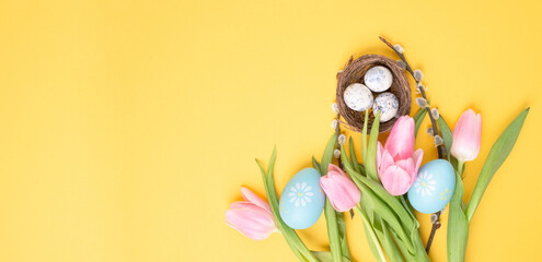 Nest with small eggs and pink tulips on a yellow colored background, easter holiday greeting card, spring season