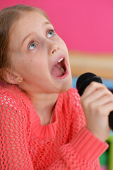 Portrait of cute little girl singing with microphone