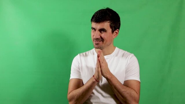 Young adult man feels good about something and rubs hands, isolated on green screen