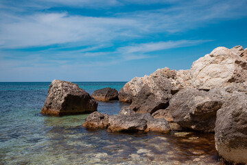 Summer seascape. Rocks and stones near the coastline. Blue sky and ocean.