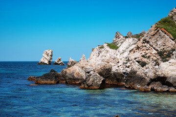 Naklejka premium Summer seascape. Rocks and stones near the coastline. Blue sky and ocean.