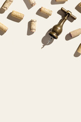 Background with wine corks and old bottle opener for white and red wine on beige pastel color with shadow at sunlight, copy space. Trend layout with bottle wood cork and corkscrew, top view table