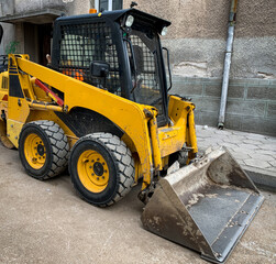 Small backhoe loader parked on a construction site. Compact tractor backhoe loader.